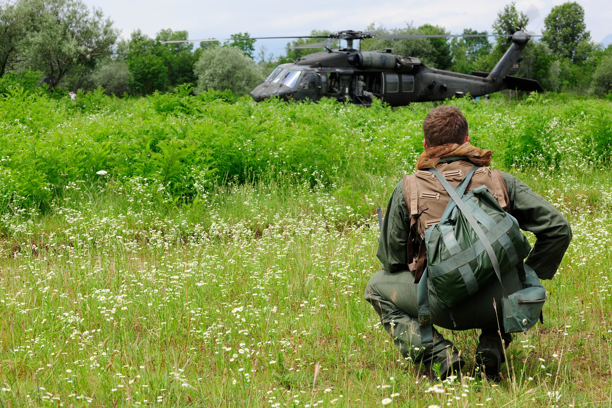 U.S. Air Force Capt. William Flynt, 555th Fighter Squadron F-16 Fighting Falcon pilot, waits for a U.S. Army UH-60 Black Hawk helicopter during a combat search and rescue training mission, June 24, 2014, at Cellina Meduna training ground near Maniago, Italy. Pilots are taught necessary survival skills to evade capture and get recovered successfully to include: movement, camouflage and signaling techniques. (U.S. Air Force photo/Airman 1st Class Ryan Conroy)
