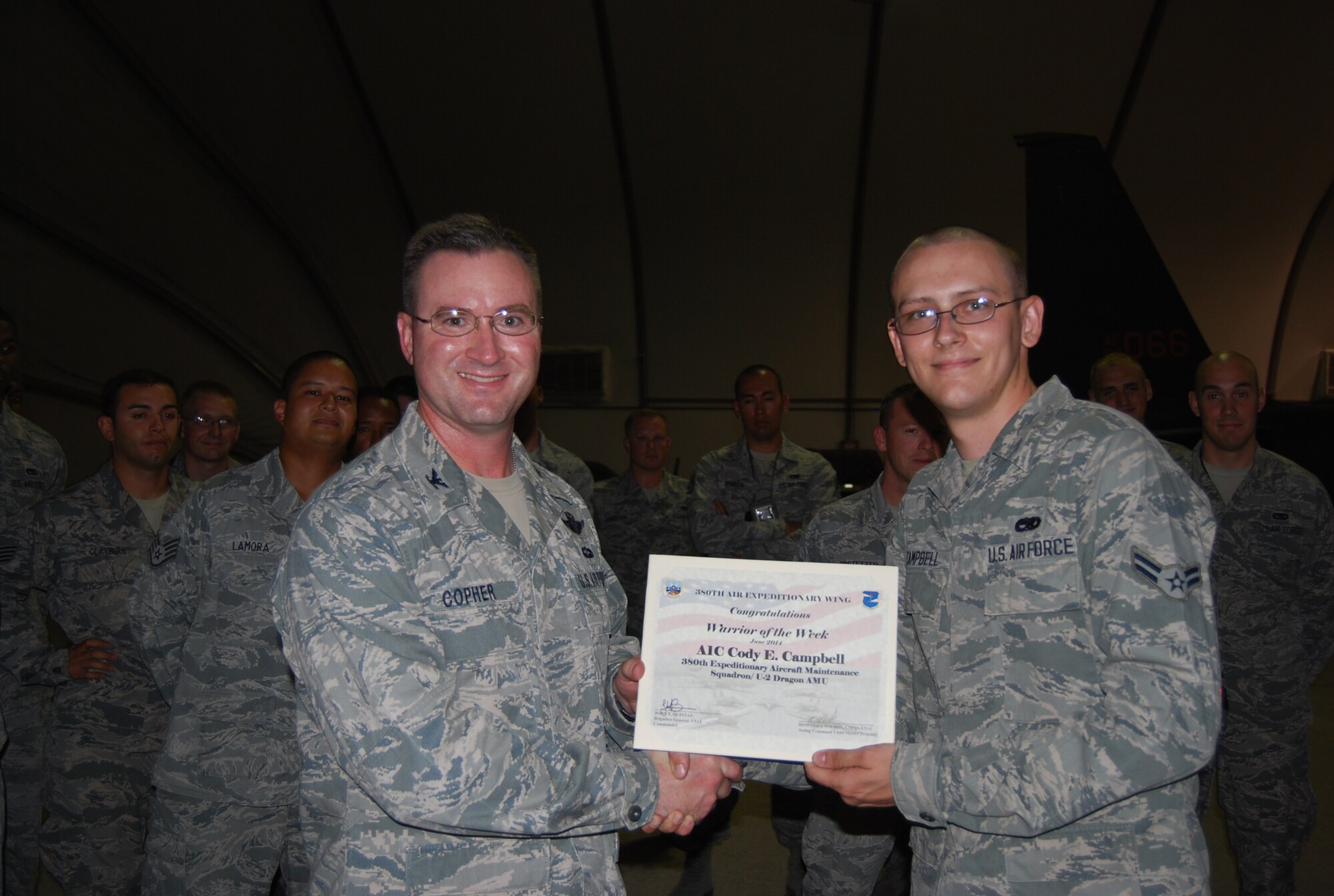 Col. James Copher, 380th Air Expeditionary Wing vice commander, presents Airman 1st Class Cody Campbell, 380th Expeditionary Aircraft Maintenance Squadron, a warrior of the week certificate at an undisclosed location in Southwest Asia, June 25, 2014. Campbell, a native of Mesa, Ariz., is deployed from Beale Air Force Base, Calif (courtesy photo/Released)