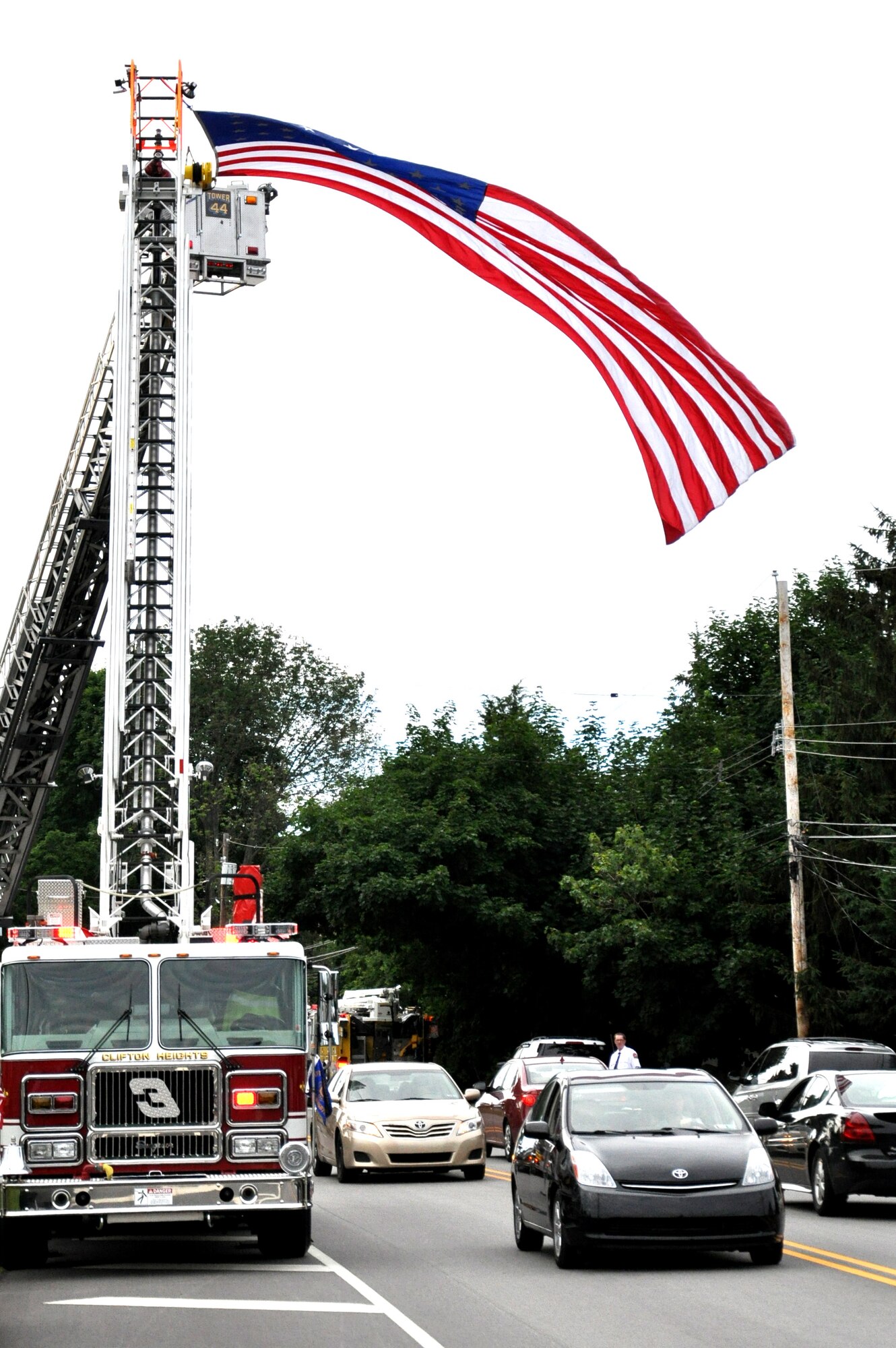A fire engine uses its ladder to display an American Flag in honor of more than 150 World War II and Korean War veterans who returned from visiting their respective monuments in Washington, D.C., June 21, 2014, outside of St. Kevin’s Church, Springfield, Pa.  Honor Flight Philadelphia escorted the veterans to the nation’s capital and to Arlington National Cemetery, Virginia.  Upon their return, they were greeted by more than 700 people, including service members from Joint Base McGuire-Dix-Lakehurst, N.J. (U.S. Air Force photo by 2nd Lt. Carrie Volpe/Released)