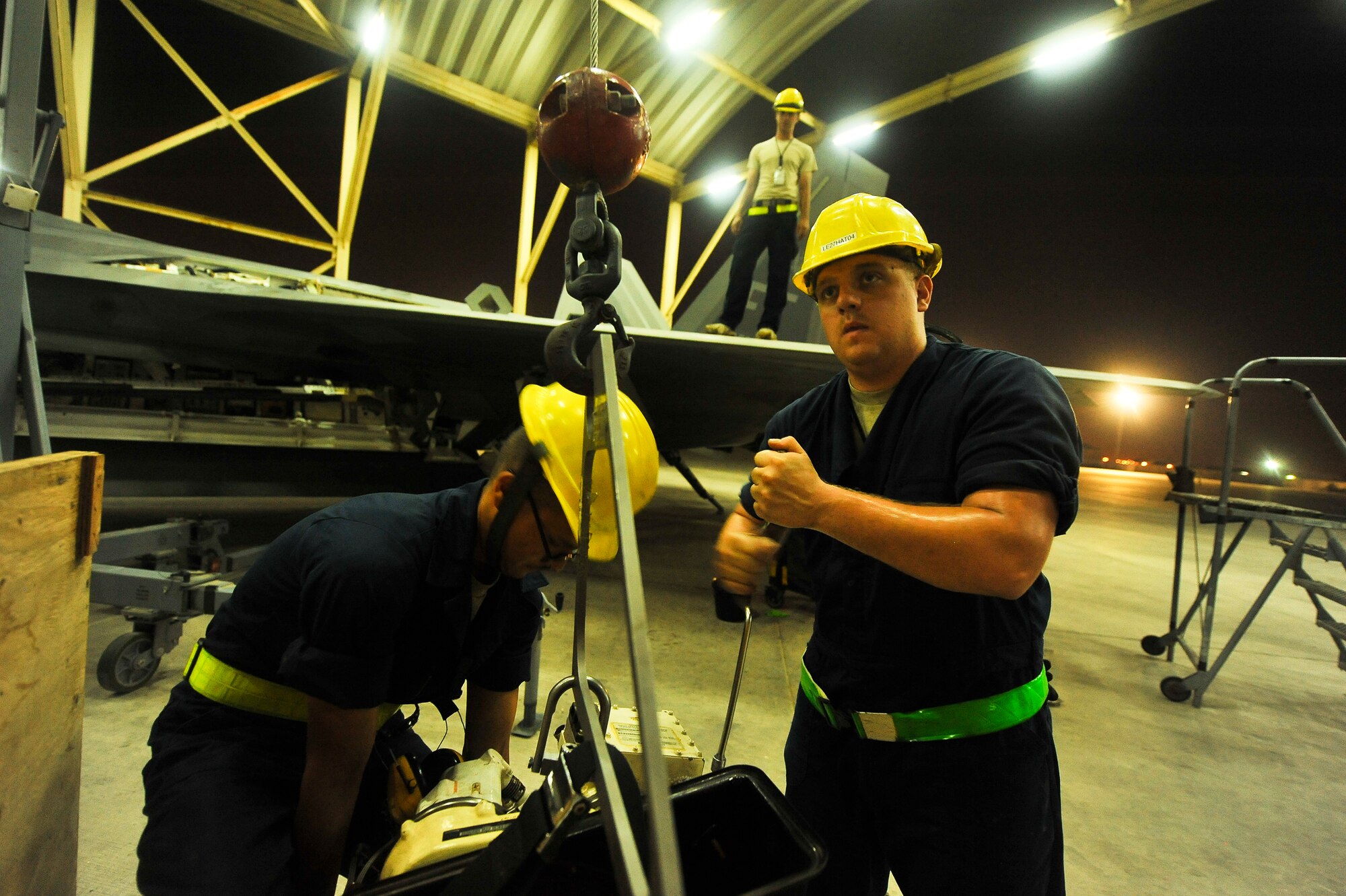 Senior Airman John-Anthony Centano, Senior Airman Nicholas Banducci and Staff Sgt. Colby Bostwick, all deployed from Joint Base Langley-Eustis, Va., prepare to hoist an auxiliary power unit into an F-22A Raptor June 17, 2014, at an undisclosed location in Southwest Asia. The repair is relatively uncommon and considered heavy maintenance. (U.S. Air Force photo by Tech. Sgt. Russ Scalf/Released)