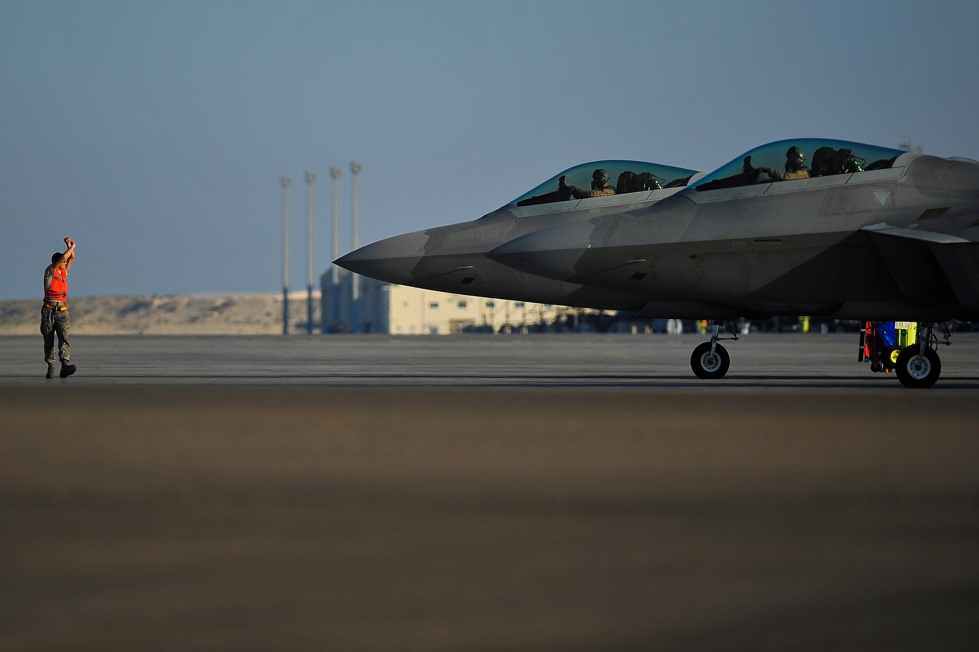 Senior Airman Jared Mast, an assistant dedicated crew chief deployed from Joint Base Langley-Eustis, Va., instructs an F-22A Raptor pilot to stop taxiing at the end of runway inspection area June 17, 2014, at an undisclosed location in Southwest Asia. The EOR is the last inspection point for aircraft prior to takeoff. (U.S. Air Force photo by Tech. Sgt. Russ Scalf/Released)