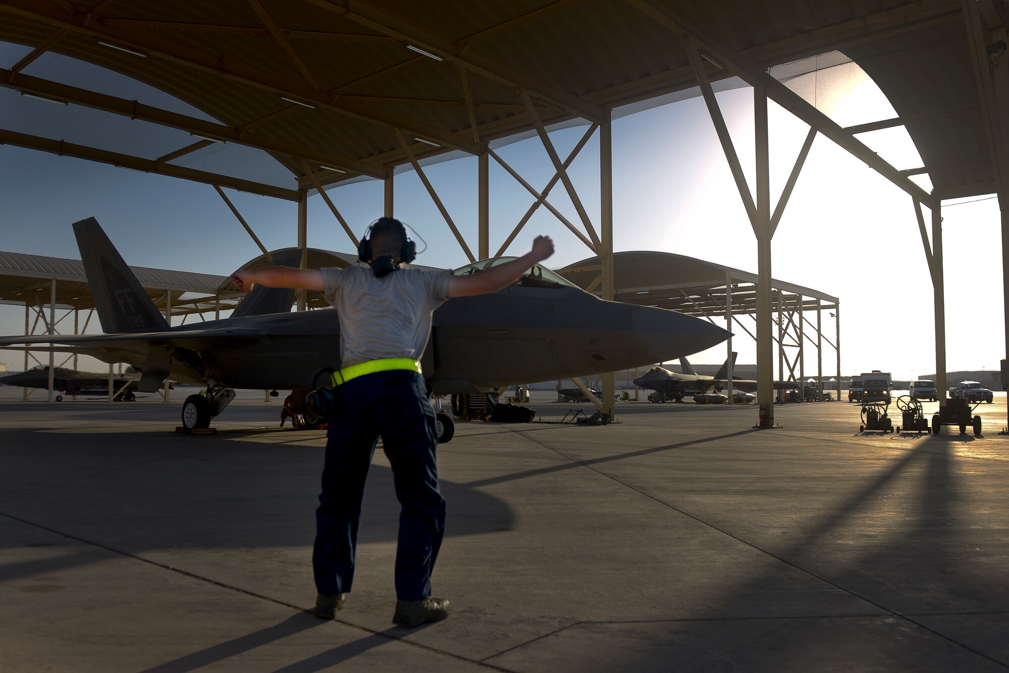 Airman Matthew Sutton, an assistant dedicated crew chief deployed from Joint Base Langley-Eustis, Va., instructs his B-Man to remove the wheel chocks from an F-22A Raptor June 17, 2014, at an undisclosed location in Southwest Asia.  Raptor maintainers provide combat-ready aircraft in support of Operation Enduring Freedom and Combined Joint Task Force-Horn of Africa. (U.S. Air Force photo by Tech. Sgt. Russ Scalf/Released)