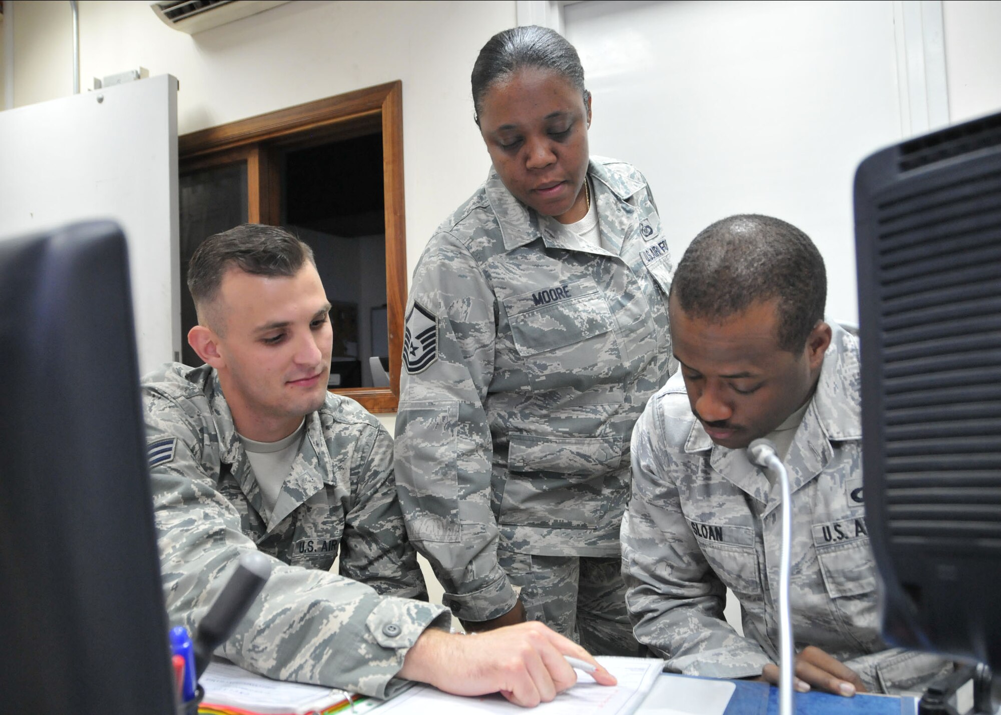 Command Post Controller Air Force Senior Airman Robert Maxwell, Command Post Superintendent Air Force Master Sgt. Eboney Moore and Command Post Controller Air Force Staff Sgt. Willie Sloan review a checklist of operations while working in the 380th Air Expeditionary Wing command post at an undisclosed location in Southwest Asia. (U.S. Air Force photo by Senior Master Sgt. Eric Peterson/Released)