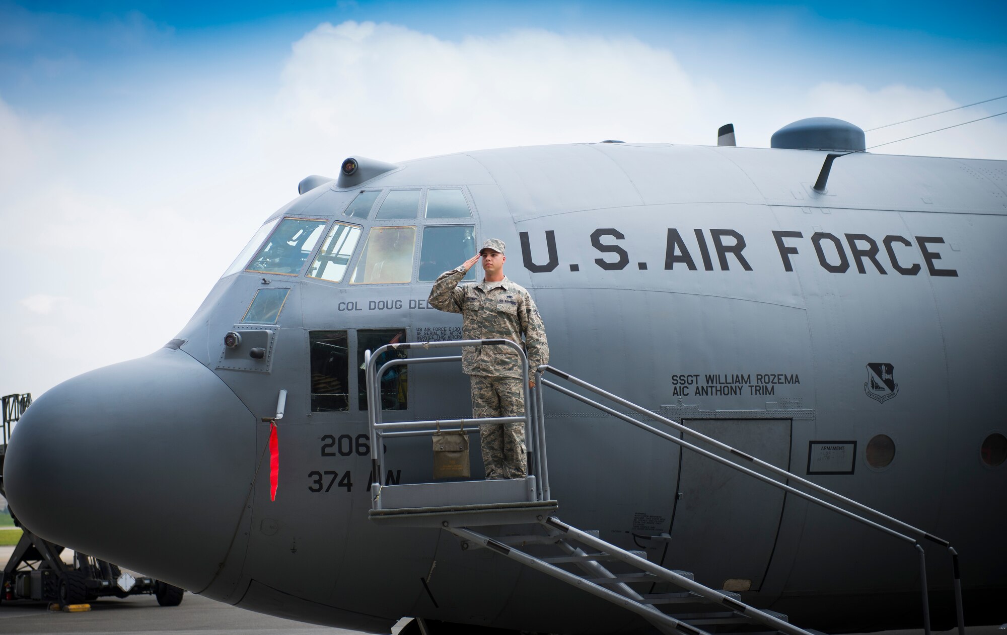 Staff Sgt. William Rozema, 374th Maintenance Squadron, salutes the new 374th Airlift Wing commander, Col. Douglas DeLaMater, after reveiling the incoming commander's name on the wing's flagship C-130 Hercules during the 374th Airlift Wing change of command ceremony at Yokota Air Base, Japan, June 26, 2014. (U.S. Air Force photo by Staff Sgt. Chad C. Strohmeyer/Released)
