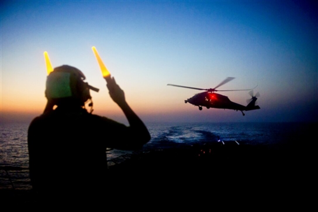 U.S. Navy Petty Officer 2nd Class Darin Kent signals to pilots in an MH-60S Seahawk helicopter as it picks up supplies from the flight deck during a vertical replenishment aboard the guided-missile destroyer USS Arleigh Burke in the Persian Gulf, June 20, 2014. The Arleigh Burke is deployed in the U.S. 5th Fleet area of responsibility supporting maritime security operations and theater security cooperation efforts. The Seahawk is assigned to Helicopter Sea Combat Squadron 26. 