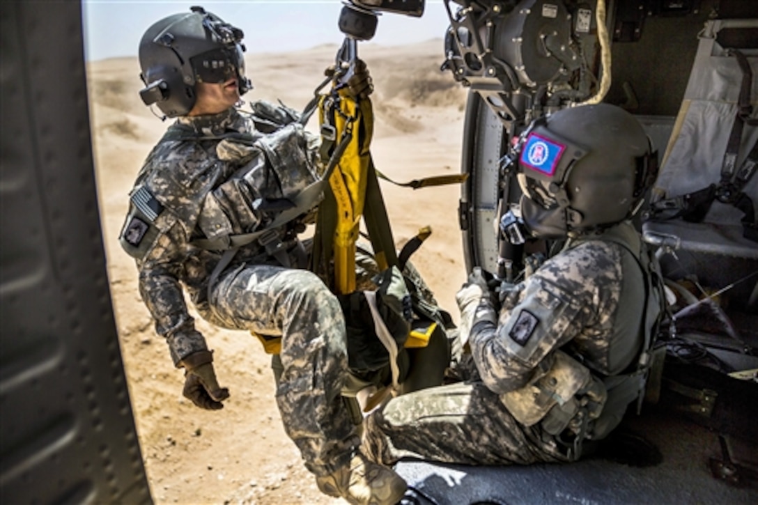 U.S. Army Spc. Giles Dunlop hoists U.S. Army Spc. Nicholas Mouyos, left, into a UH-60 Black Hawk helicopter during a personnel recovery exercise in Kuwait, June 19, 2014. Mouyos, a flight medic, and Dunlop, a crew chief, are assigned to 42nd Combat Aviation Brigade, Company C, 1st Battalion, 214th Air Ambulance. 