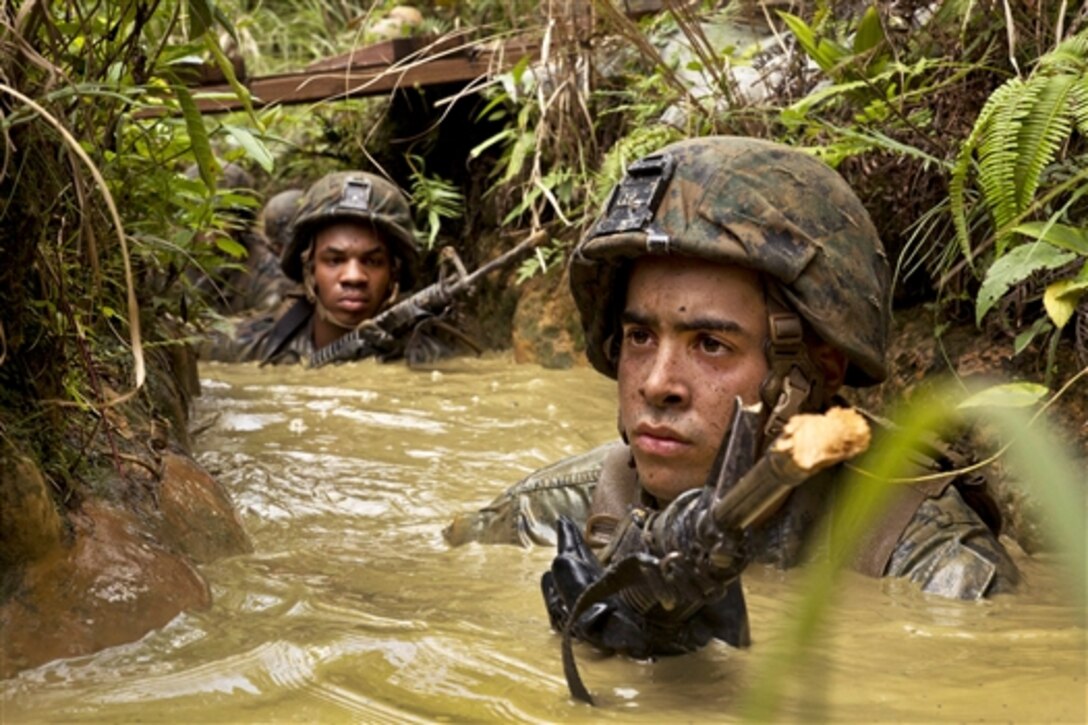 U.S. Marine Corps Cpl. Christian Hiraldo leads Marines and sailors through a mud pit during the endurance course at the Jungle Warfare Training Center on Camp Gonsalves in Okinawa, Japan, June 21, 2014. During the course, Marines and sailors navigated harsh jungle environment and man-made obstacles in the heat and humidity of the island. 
