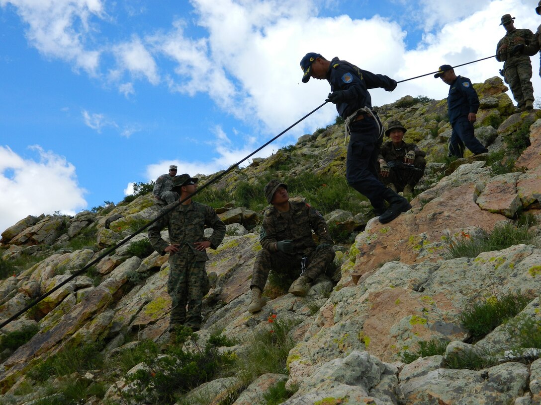 U.S. Marine Corps Staff Sgt. Gale L. Anders and Sgt. Gustavo A. Pesquera instruct members of the Mongolian Armed Forces in the proper techniques for hasty rappelling down steep rock ledges June 21 as part of the Survivor’s Course portion of Exercise Khaan Quest 2014 at the Five Hills Training Area, Mongolia. Khaan Quest is a regularly scheduled, multinational exercise co-sponsored this year by U.S. Army, Pacific, and hosted annually by Mongolian Armed Forces. KQ14 is the latest in a continuing series of exercises designed to promote regional peace and security. This year marks the 12th iteration of this training event. Anders is the operations chief for 3rd Marine Division, III Marine Expeditionary Force. Pesquera is an instructor section leader at the Jungle Warfare Training Center at Camp Gonsalves, Okinawa, Japan.