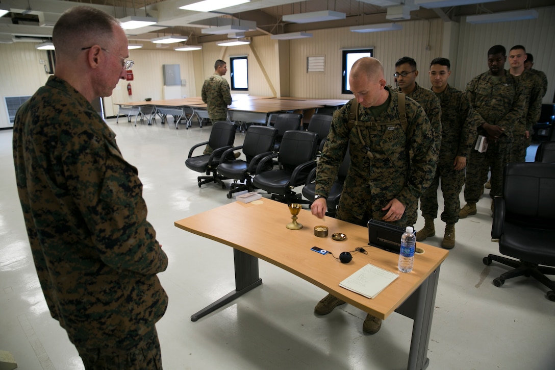 U.S. Marine 1st Sgt. Christopher R. Taylor, center right, takes part in communion at a church service hosted by U.S. Navy Lt. Cmdr. Jeffrey A. Terry, left, June 8 at Warrior Base, Munsan, South Korea. The service reinforced morale for the Marines by giving them a break from the daily tasks associated with the exercise. Taylor is the first sergeant for Headquarters Battery, 12th Marine Regiment, 3rd Marine Division, III Marine Expeditionary Force. Terry is a Jacksonville, Florida, native and chaplain for the regiment.