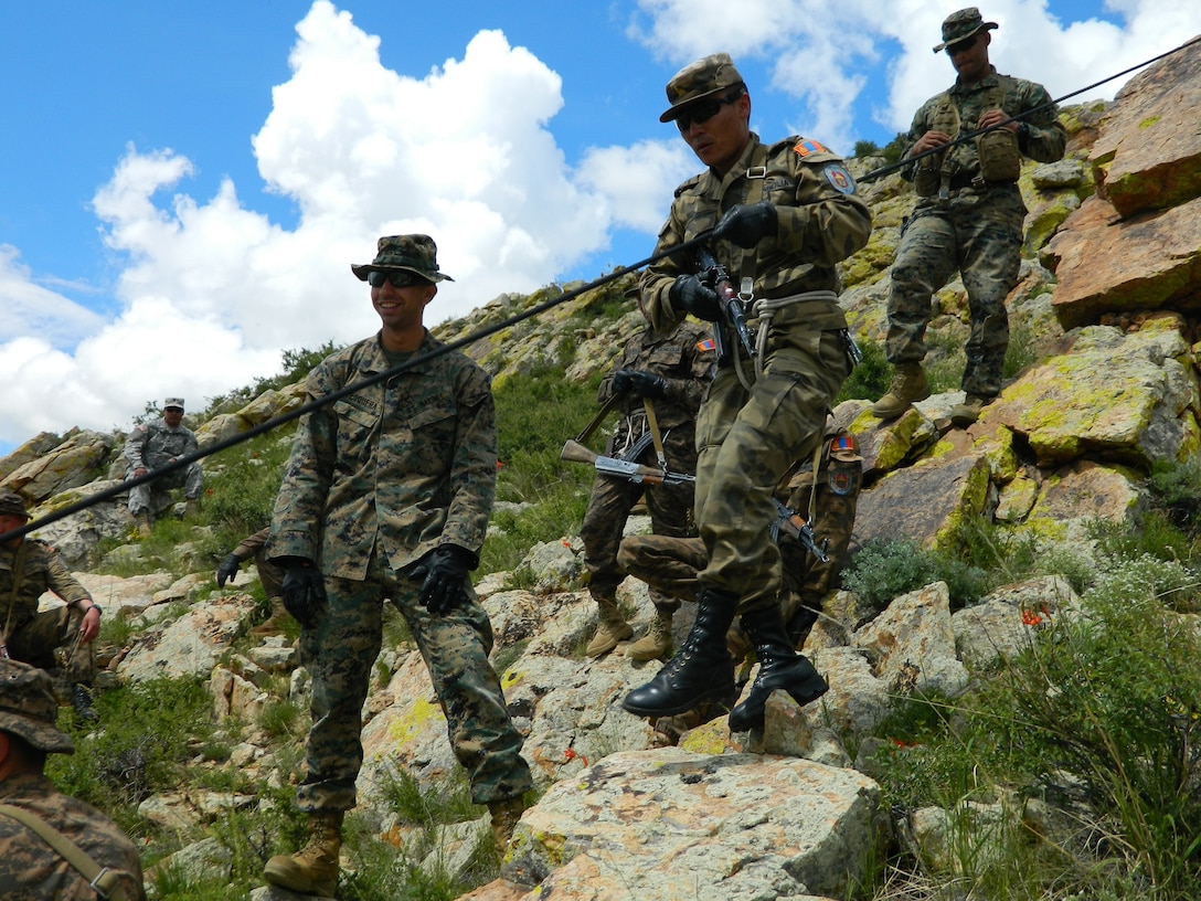 U.S. Marine Corps Staff Sgt. Gale L. Anders and Sgt. Gustavo A. Pesquera instruct members of the Mongolian Armed Forces in the proper techniques for hasty rappelling down steep rock ledges June 21, 2014 as part of the Survivor’s Course portion of Exercise Khaan Quest 2014 at the Five Hills Training Area, Mongolia. Khaan Quest is a regularly scheduled, multinational exercise co-sponsored this year by U.S. Army, Pacific, and hosted annually by Mongolian Armed Forces. KQ14 is the latest in a continuing series of exercises designed to promote regional peace and security. This year marks the 12th iteration of this training event. Anders is the operations chief for 3rd Marine Division, III Marine Expeditionary Force. Pesquera is an instructor section leader at the Jungle Warfare Training Center at Camp Gonsalves, Okinawa, Japan.