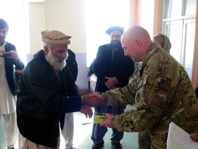 Army Sgt. Maj. Lynward Hall, the Georgia Agribusiness Development Team Ag Team non-commissioned officer in charge, presents a local Wardak Province farmer with a Certificate of Training and a radio. Attendees who attended both days of small-business training received a certificate and radio.