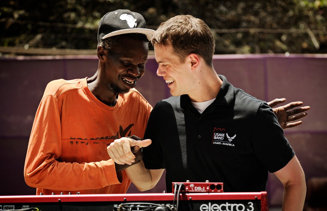 Senior Airman Mike Mitchell laughs with a Senegalese musician during a concert June 14, 2014, at a local cultural center in Dakar, Senegal. U.S. Air Forces in Europe and Air Forces Africa Airmen were in Senegal for the African Partnership Flight, a program designed to improve communication and interoperability between regional partners in Africa. The band played multiple venues in the area to inspire children and musicians through the universal language of music. Mitchell is a keyboardist with the USAFE-AFRICA band. (U.S. Air Force photo/Staff Sgt. Ryan Crane)