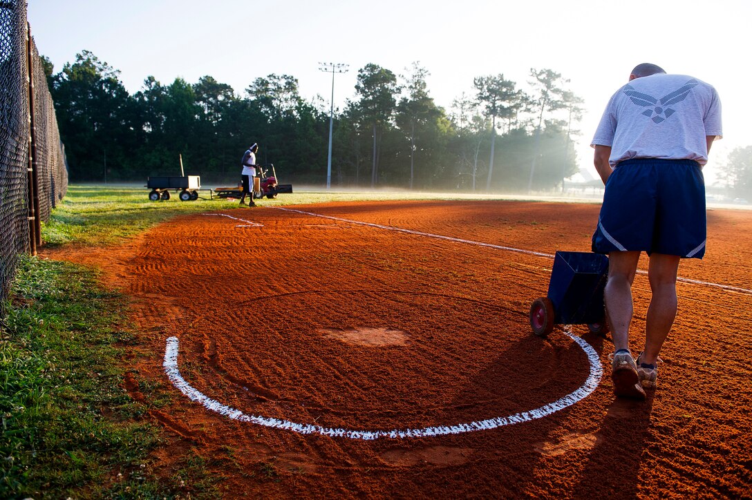 Staff Sgt. Lakan Ello uses a chalk dispenser to make an on-deck circle June 18, 2014, at Joint Base Charleston, S.C. New chalk lines are put down every game day to keep the field maintained for the players. Ello is a fitness specialist with the 628th Force Support Squadron. (U.S. Air Force photo/Senior Airman George Goslin)
