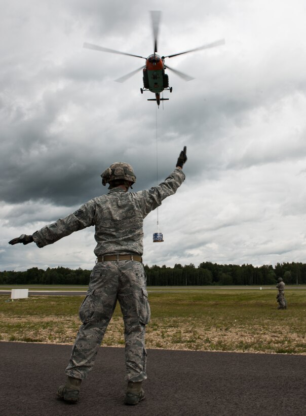 Staff Sgt. Timothy Kennedy marshals a Latvian Mi-8 helicopter in part of sling-load operations training during the Air Force-specific portion of Saber Strike June 17, 2014, on Lielvarde Air Base, Latvia. During the final week of Saber Strike 2014 the 435th Contingency Response Group, in conjunction with the 37th Airlift Squadron, trained on the full capabilities to open the Latvian air base. They also trained with Latvian and Estonian service members on airfield operations, command and control of air and space forces, weather support, and protection of operational forces, aircraft maintenance, and aerial port services. Kennedy is assigned to the 435th Security Forces Squadron. (U.S. Air Force photo/Senior Airman Jonathan Stefanko)