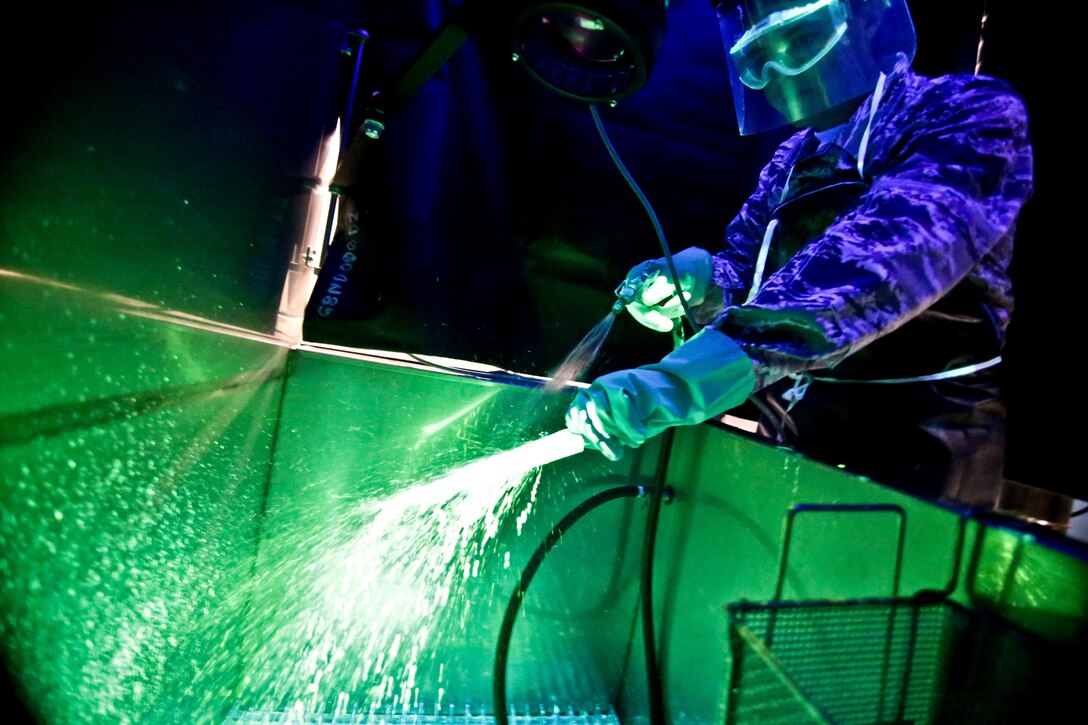 Airman 1st Class Cory Kalin sprays a piece of metal during a penetrant test June 18, 2014, on Atlantic City Air National Guard Base, N.J. Penetrant testing is a method of detecting surface cracks, corrosion, scratches and other surface impurities which create cavities and voids on the surface of metals or other structural materials. Kalin is a nondestructive inspection specialist with the New Jersey Air National Guard's 177th Aircraft Maintenance Squadron. (U.S. Air National Guard photo/Tech. Sgt. Matt Hecht)