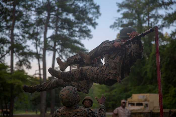 Marines with 2nd Supply Battalion, Combat Logistics Regiment 25, 2nd Marine Logistics Group climb over a high bar at the start of an endurance course aboard Camp Lejeune, N.C., June 26, 2014. Approximately 50 noncommissioned officers and two officers ran the endurance course during a motivational exercise designed to test the NCOs.