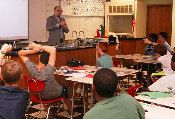Chris Strunk, a structural engineer with the Tulsa District U.S. Army Corps of Engineers, speaks to youngsters at the Cascia Hall science, technology, engineering, and math summer camp June 18. He is holding a chunk of concrete as he explains the benefits of the use of concrete in building bridges.                   