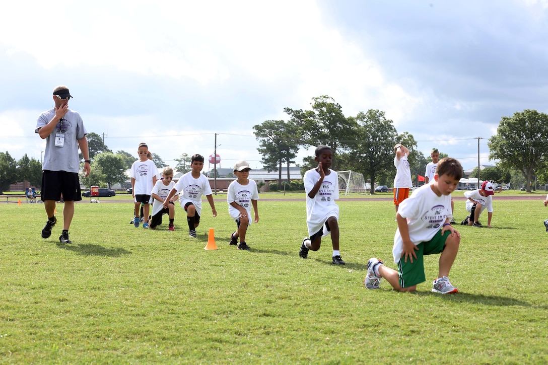 Campers of the Steve Smith ProCamp start the day with stretching exercises at Marine Corps Air Station Cherry Point, N.C., June 24, 2014. The installation was selected to host the ProCamp for the second consecutive year after winning a contest between commissaries throughout the country. The camp taught campers from first to eighth grades the fundamental techniques of football.