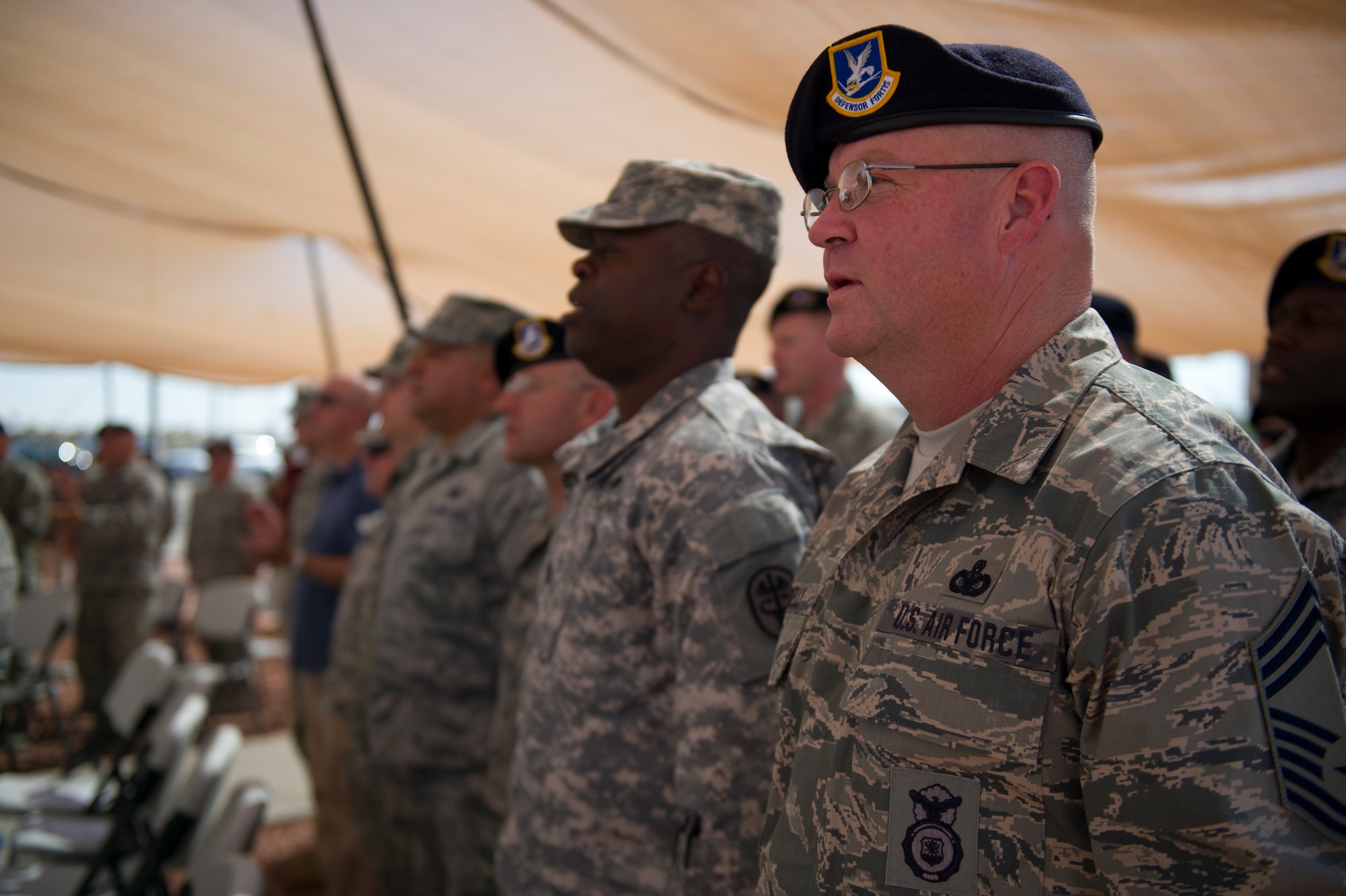 Military Police personnel from both the Air Force and Army sing the Air Force song during the opening ceremony of the Ground Command Readiness Training Center assumption of command at Fort Bliss, Texas, June 26. The GCRTC consolidated a regional training center for all the military police personnel from both Air Force and Army to use to conduct required pre-deployment training. (U.S. Air Force photo by Airman 1st Class Aaron Montoya / Released)