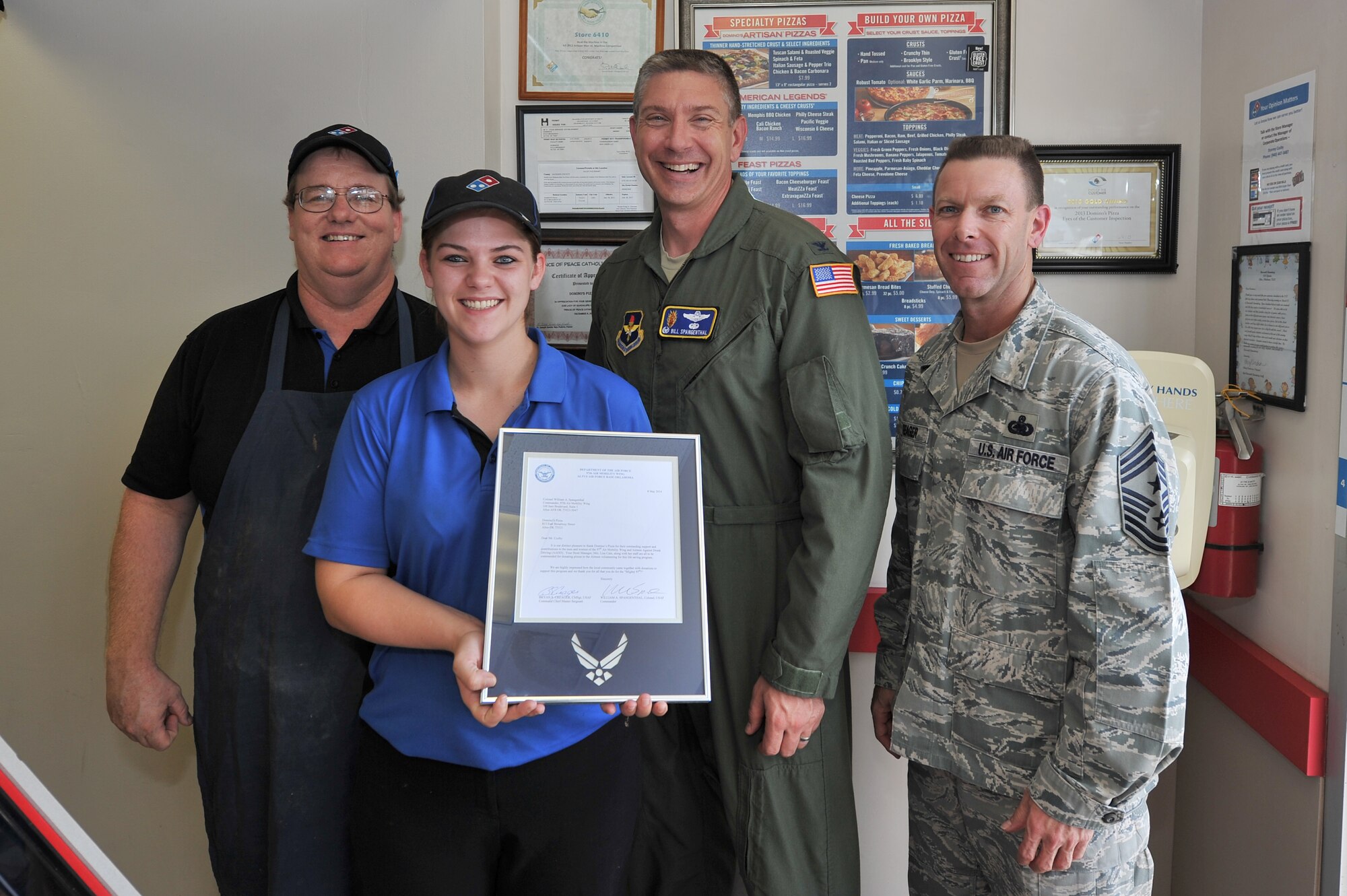 ALTUS, Okla. – U.S. Air Force Col. Bill Spangenthal, 97th Air Mobility Wing commander, and Chief Master Sgt. Bryan Creager, 97th AMW command chief, present a letter of appreciation to Stormy Cozby and Kay Leigh of Domino’s Pizza in Altus June 27, 2014. The letters of appreciation were presented to the members of Domino’s Pizza for donating pizzas to Airmen Against Drunk Driving volunteers. AADD is a program that provides a safe alternative for base members to help eliminate drinking and driving. (U.S. Air Force photo by Senior Airman Dillon Davis/Released)