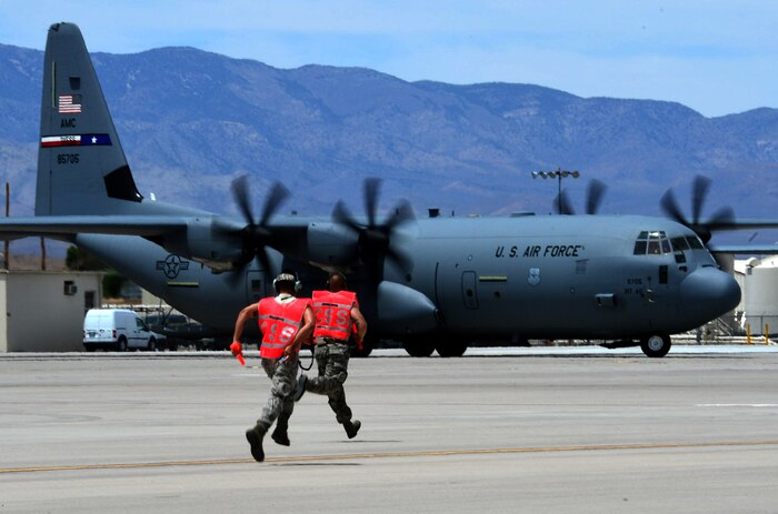 Airmen from the 818th Contingency Response Group, McGuire Air Force Base, N.J., run toward a C-130J Super Hercules from Dyess AFB, Texas, after it lands on the runway at Creech AFB, Nev., June 21, 2014. The 818th CRG Airmen and the aircraft participated in Joint Forcible Entry, an exercise designed to enhance service cohesiveness between the U.S. Army and Air Force. Both services work together to properly execute large scale heavy equipment and troop movement. (U.S. Air Force photo by Tech. Sgt. Nadine Barclay/Released)