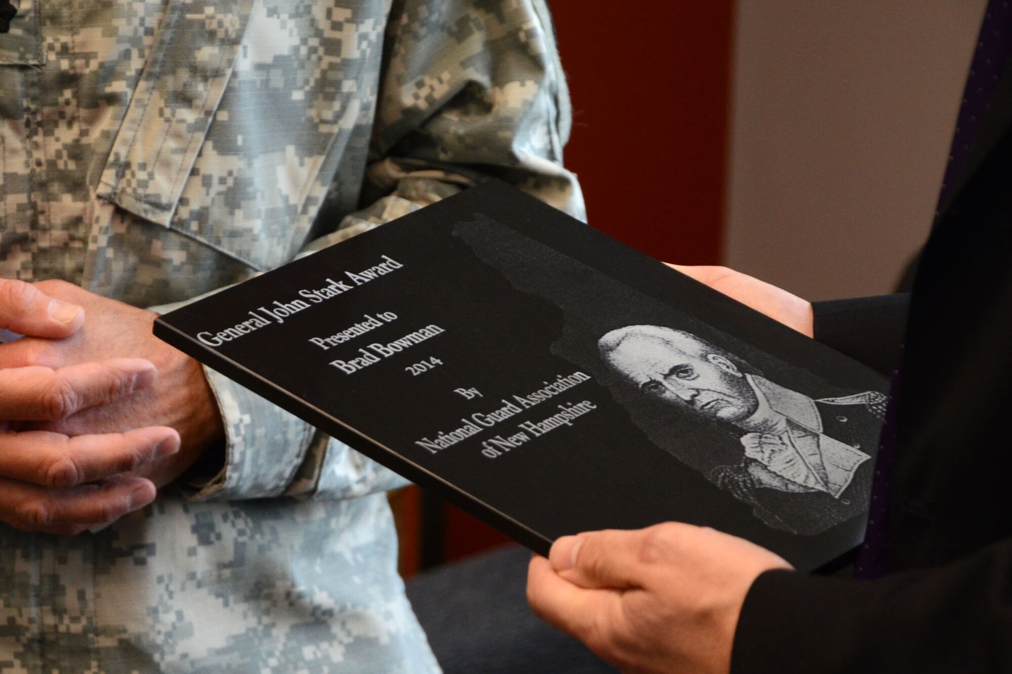 PEASE AIR NATIONAL GUARD BASE, N.H. – Brad Bowman, the senior military legislative assistant for U.S. Senator Kelly Ayotte, holds the General John Stark Award in his hand after being presented it by N.H. Army National Guard Lt. Col. Roy Hunter, president of the National Guard Association of N.H., during a visit to the base June 27. Bowman was given the award for his efforts in obtaining funding for the Deployment Cycle Support – Care Coordination Program and the 157 ARW’s quest to receive the KC-46A refueling tanker while in his role as senior military legislative lead to the senator. (N.H. Air National Guard photo by Tech. Sgt. Mark Wyatt)