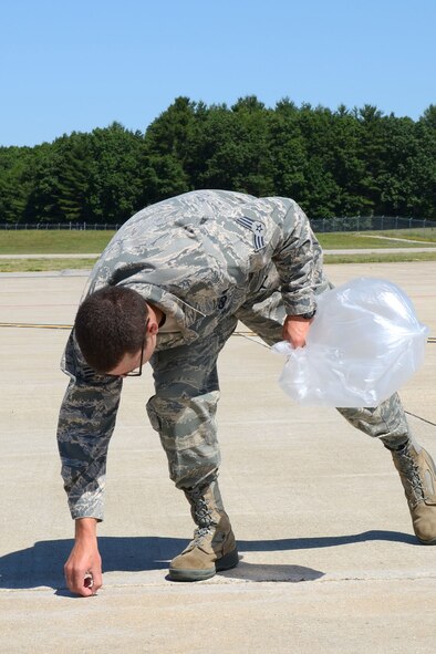 PEASE AIR NATIONAL GUARD BASE, N.H. – Senior Airmen Aaron Loring, 157th Comptroller Squadron, reaches down to pick up foreign object debris on the flightline here June 27. Loring and more than 50 others participated in the foreign object debris walk, or FOD walk, which collected more than 40 pounds of debris. Among the items collected were bolts, safety wire, vehicle parts and more. (N.H. Air National Guard photo by Tech. Sgt. Mark Wyatt)