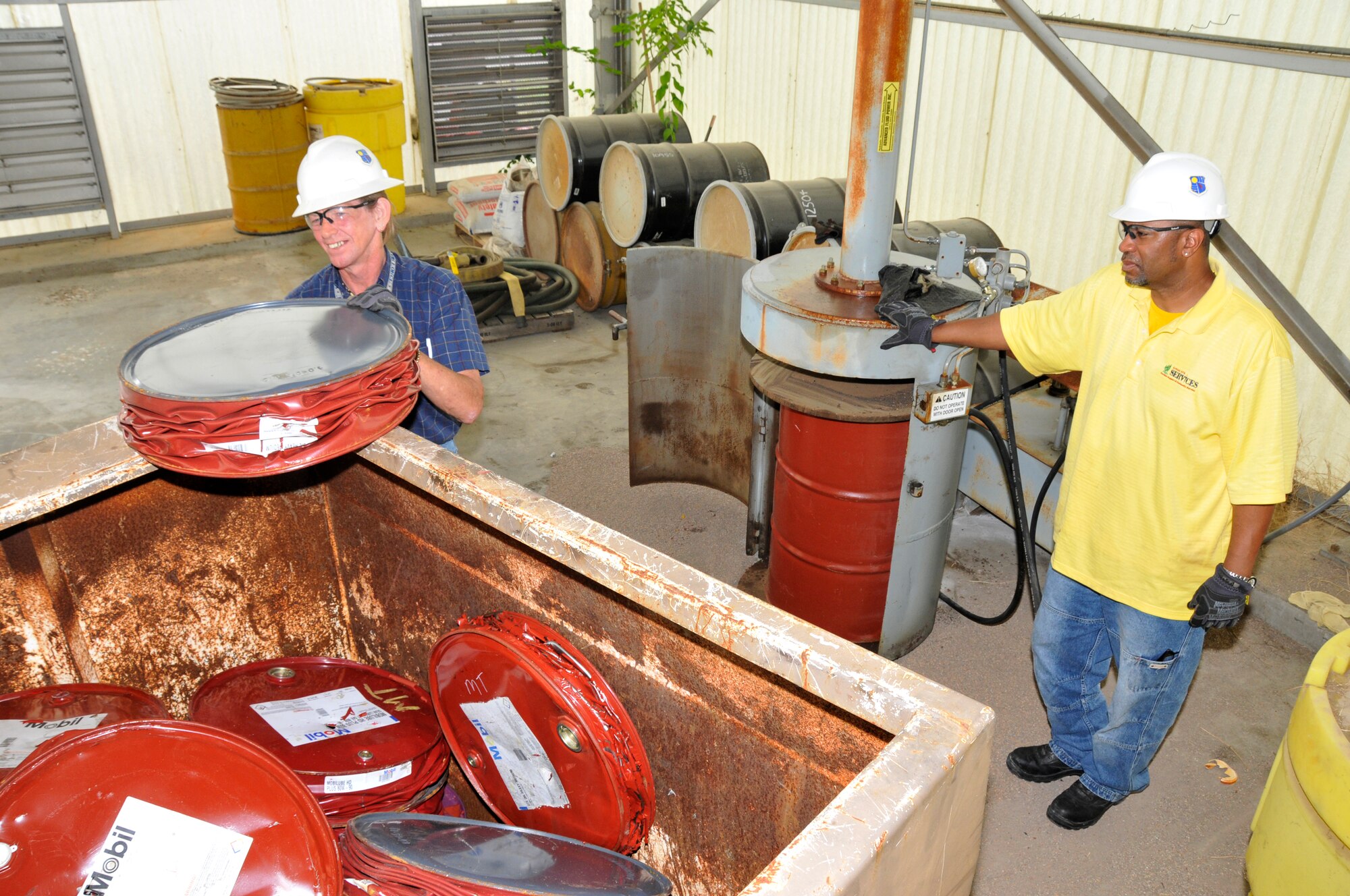 Personnel at AEDC’s Recycling Facility crush empty steel drums that have been collected from various areas on base. After being crushed down to approximately 6-inches in height, the drums are then placed in a bin to be recycled. Pictured are Doug Richards and Charles Wilkerson with the AEDC Services Office. (Photo by Rick Goodfriend) 