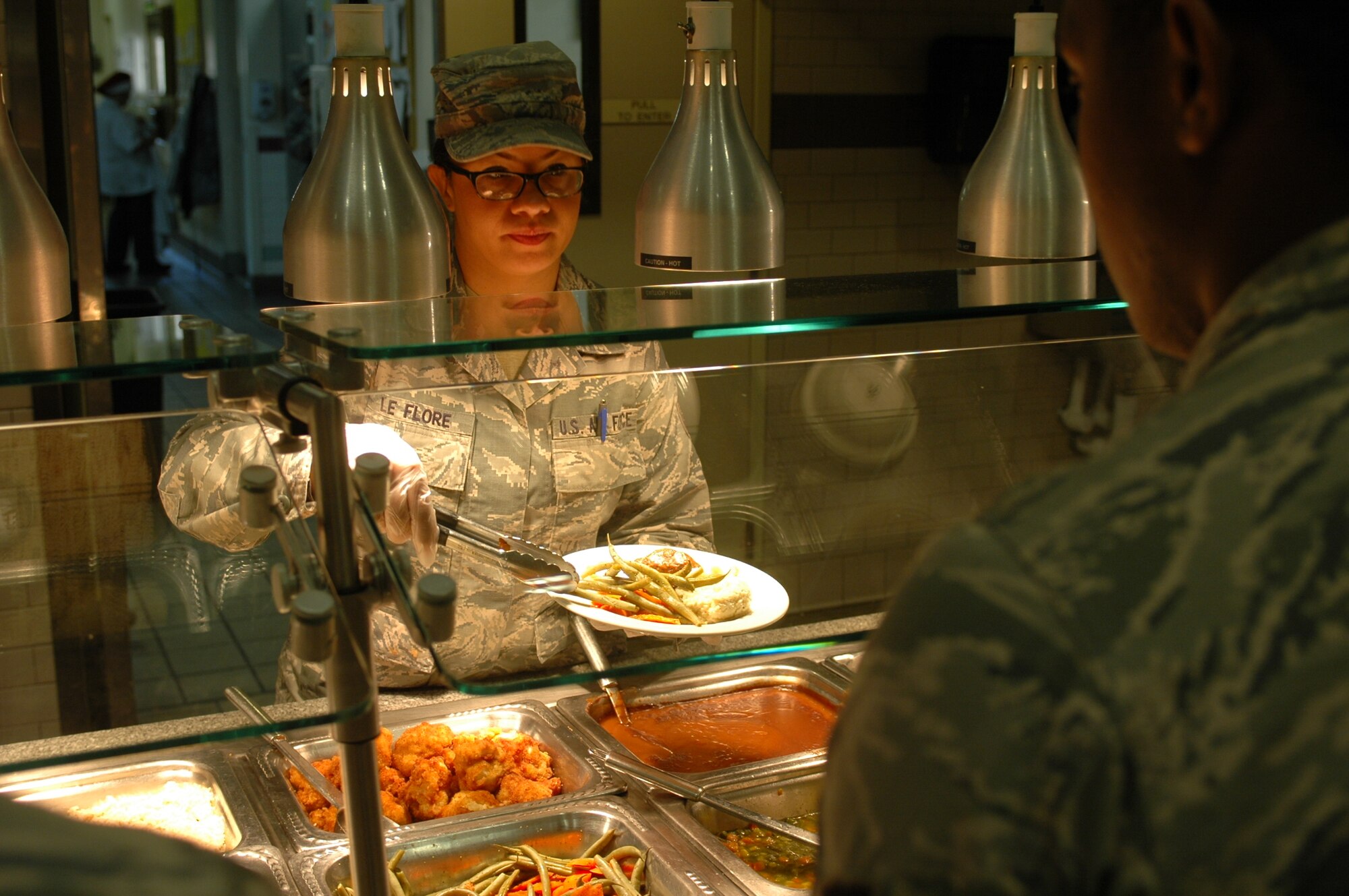 Senior Airman Samantha LeFlore, 60th Force Support Squadron food production chef, serves vegetables to an awaiting Airman during the lunch rush at the Sierra Inn Dining Facility June 23. The Sierra Inn team, consisting of Airmen, civil service workers, PRIDE Industry and ARAMARK employees, serves approximately 1,000 meals every day.