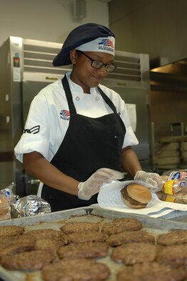 Airman 1st Class Michelle Harmon, 60th Force Support Squadron food production chef, prepares hamburgers at the Sierra Inn Dining Facility for the Knucklebuster Café June 23. The staff at the Sierra Inn provide 24-hour support to the Knucklebuster Café to ensure Airmen on the flightline have food available to them. (U.S. Air Force photo/Senior Airman Bryan Swink)