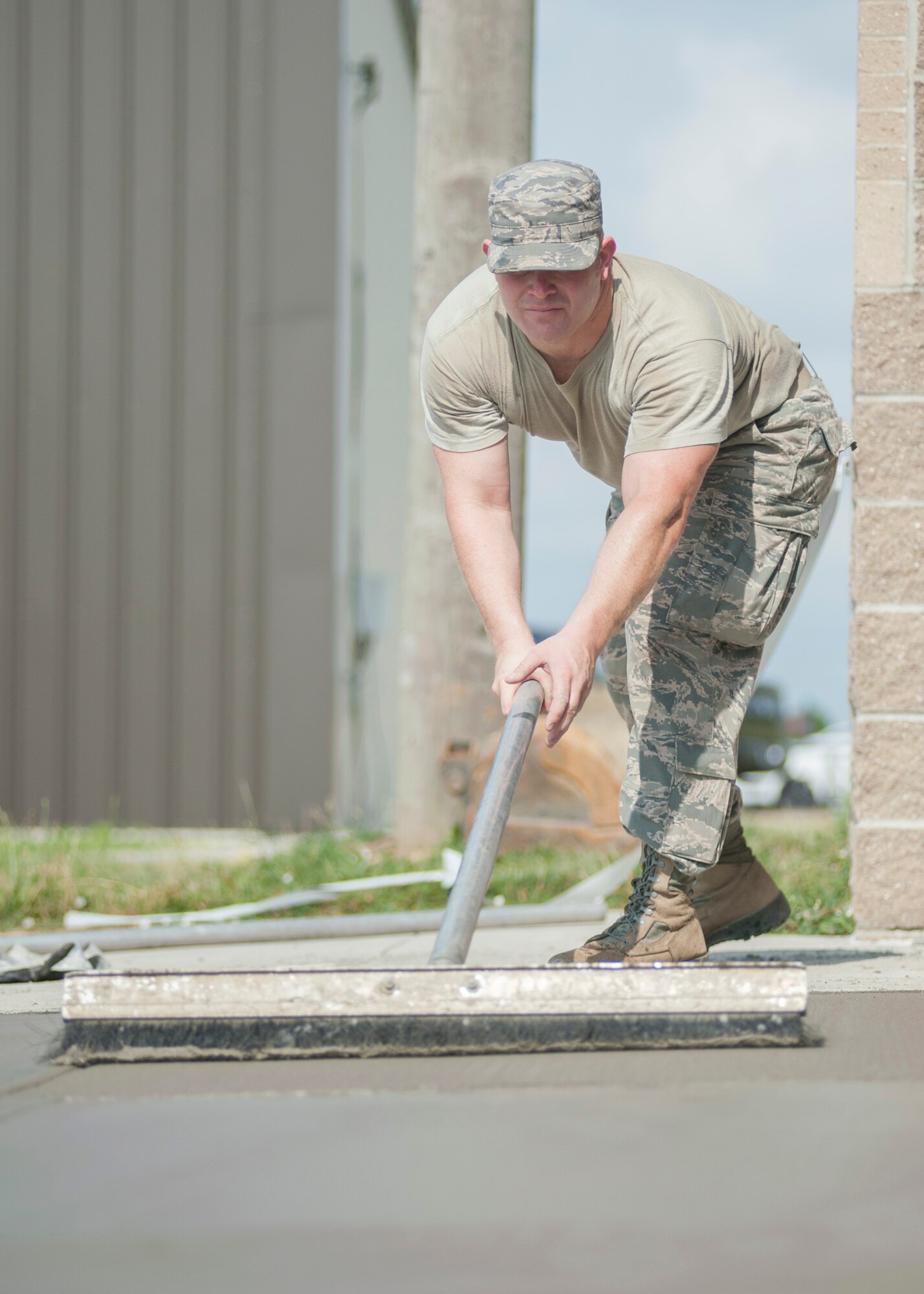 Tech Sgt. Matthew Haverly, 436th Civil Engineer Squadron payment and equipment operator, applies texture to fresh concrete June 25, 2014, on Dover Air Force Base, Del. The concrete was set to give combat arms instructors a safe working driveway to load and offload ammunition for their classes. (U.S. Air Force photo/Senior Airman Jared Duhon) 