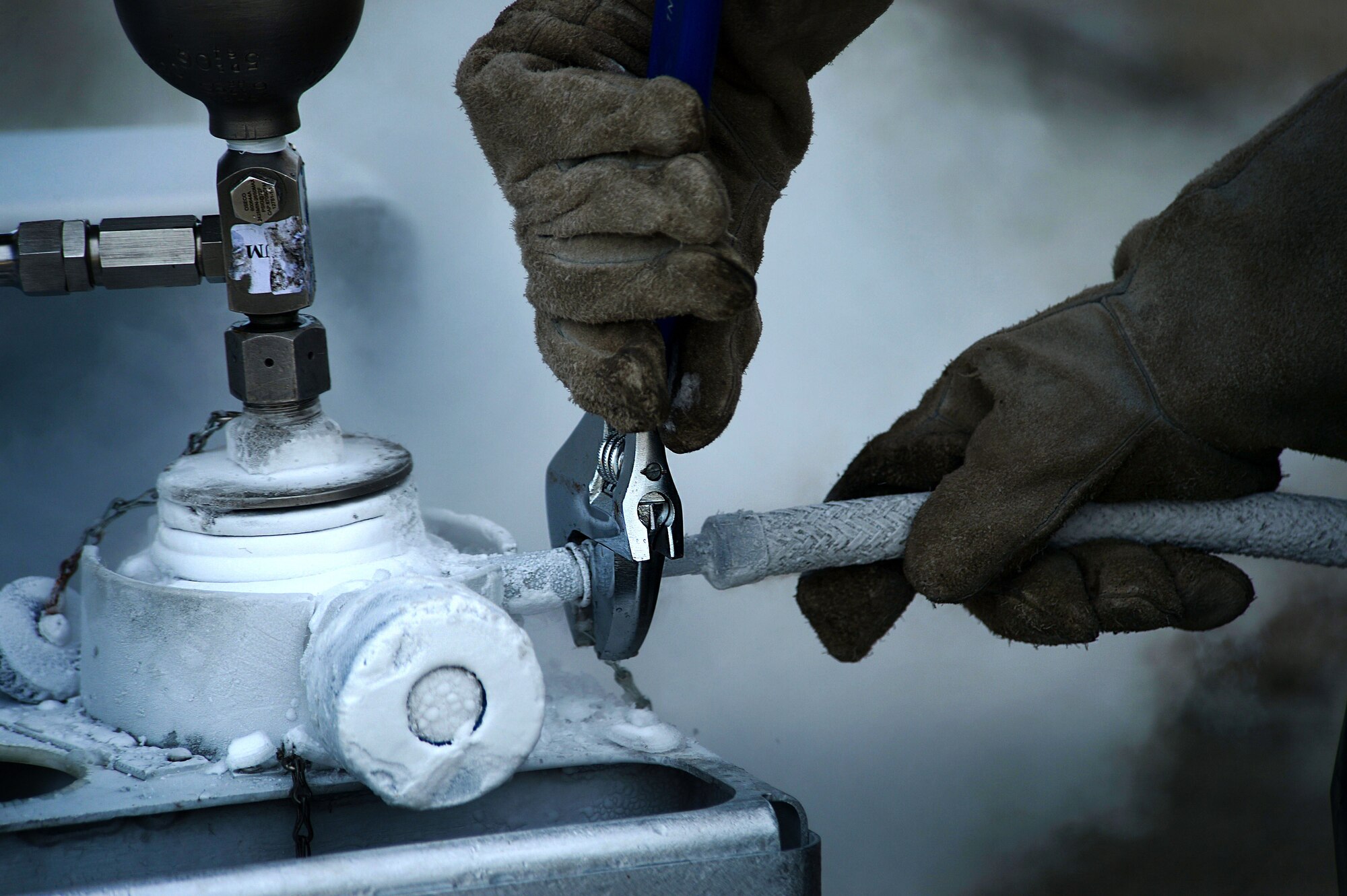 A 20th Logistics Readiness Squadron fuels fixed facilities technician, loosens a hose attached to a liquid oxygen sampling kit at Shaw Air Force Base, S.C., June 26, 2014. While performing the routine sampling, Airmen wear two pairs of gloves, protective overalls, face shield and apron for protection from the -298 degree Fahrenheit liquid. (U.S. Air Force photo by Airman 1st Class Jensen Stidham/Released) 