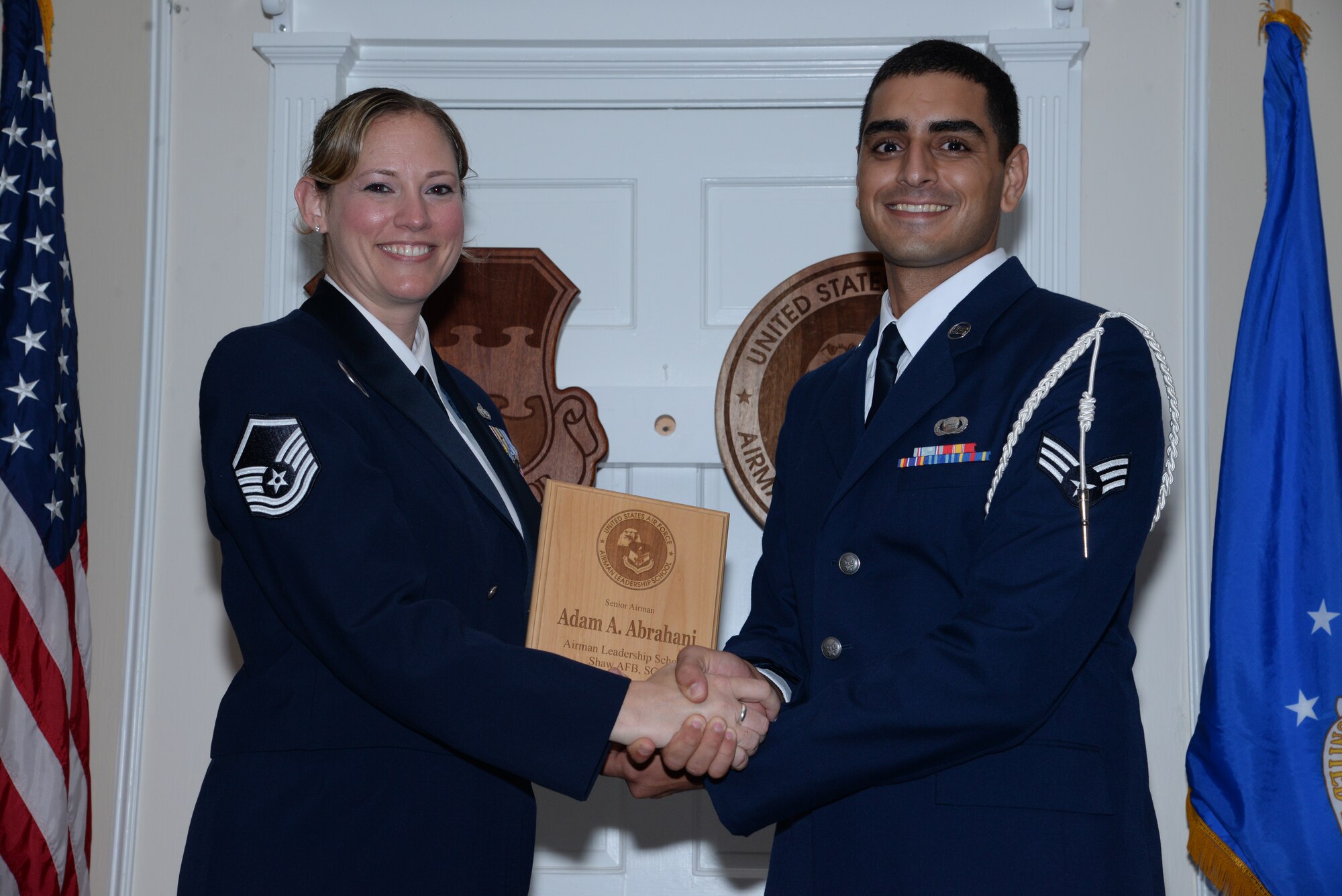 U.S. Air Force Senior Airman Adam Abrahani, 3rd Intelligence Squadron (right), receives the Senior Master Sgt. David B. Reid Airman Leadership School Class 14-5 Commandant’s Award from Master Sgt. Lindsey Wolf, ALS commandant, during the class’ graduation ceremony at Shaw Air Force Base, S.C., June 26, 2014. The award is given to the Airman who best exemplifies professional military qualities as chosen by their peers, the ALS instructors, and the commandant. (U.S. Air Force photo by Airman 1st Class Jonathan Bass/Released)