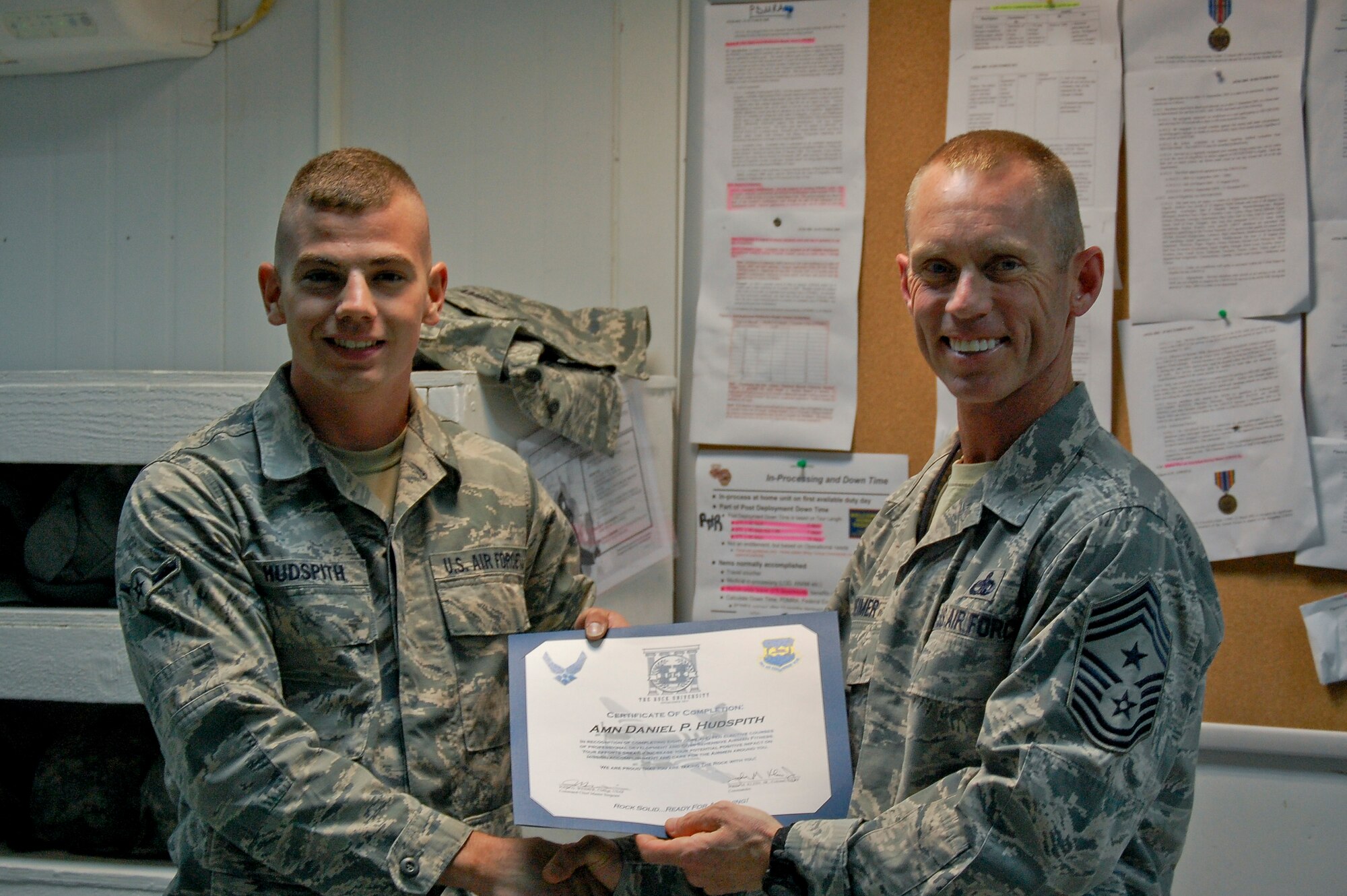 U.S. Air Force Chief Master Sgt. John Weimer, 386th Air Expeditionary Wing command chief, presents Airman Daniel Hudspith, 386th Expeditionary Logistics Readiness Squadron air transportation journeyman, with his Rock University certificate June 19, 2014 at an undisclosed location in Southwest Asia. Hudspith is among the first to graduate from the program since its inception last April. (U.S. Air Force courtesy photo)