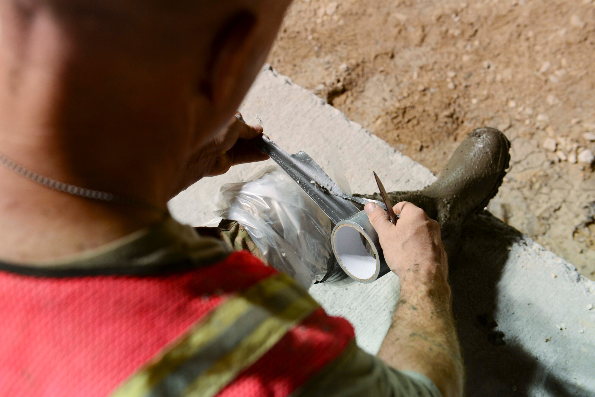 U.S. Air Force Master Sgt. Chris Coyne, 557th Expeditionary RED HORSE Squadron, tapes plastic around his boots before concrete pouring at Al Udeid Air Base, Qatar, June 23, 2014. The concrete pad will be part of a permanent pad to support maintenance operations under a new sunshade at AUAB. Coyne is deployed from Horsham Air Guard Station, Pennsylvania. (U.S. Air Force photo by Staff Sgt. Ciara Wymbs)  