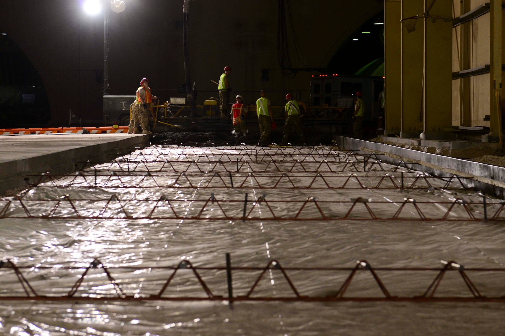 U.S. Air Force Airmen assigned to the 557th Expeditionary RED HORSE Squadron work to pour concrete at Al Udeid Air Base, Qatar, June 23, 2014. The concrete pad will be part of a new taxi lane for aircraft maintenance under a new sun shade at AUAB. (U.S. Air Force photo by Staff Sgt. Ciara Wymbs)  