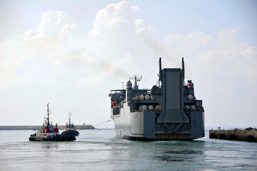 Tugboats guide the container ship MV Cape Ray away from a pier at Naval ...