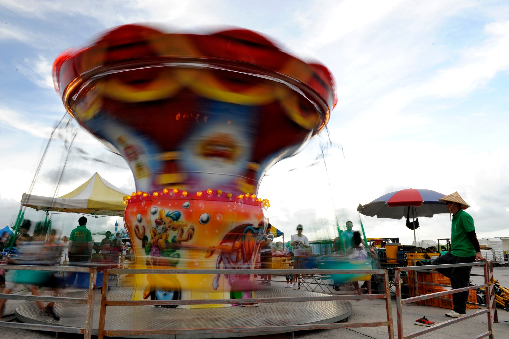 A staff member watches children ride carnival swings during AmericaFest 2014 on Kadena Air Base, Japan, June 28, 2014. The event, which included food, games and entertainment from both Okinawan and American sources, also hosted U.S. Air Force, Marine Corps and Navy as well as Japan Air-Self Defense Force aircraft to showcase the alliance between the different services and forces. (U.S. Air Force photo by Senior Airman Maeson L. Elleman)