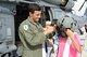 U.S. Air Force 1st Lt. Kurt Wallin, assigned to the 33rd Rescue Squadron, helps a festivalgoer put on a helmet pilots use while flying in the HH-60 Pave Hawk helicopter, Kadena Air Base, Japan, June 29, 2014. AmericaFest is an Independence Day celebration showcasing various Japanese and U.S. military aircraft. There were also games, food, live performances and other entertainment for AmericaFest attendees to enjoy. (U.S. Air Force photo by Airman 1st Class Stephen G. Eigel)