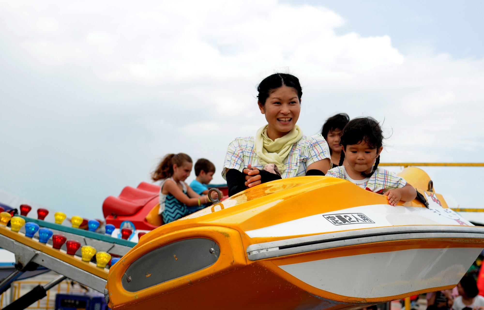 Visitors attending America Fest 2014 ride a carnival ride at Kadena Air Base, Japan, June 29.  America Fest is a two-day event which allows the local Okinawan population and military members from around Okinawa to experience a Fourth of July celebration through activities such as music, carnival rides, aircraft static displays and fireworks. (U.S. Air Force photo by Airman 1st Class Keith James)
