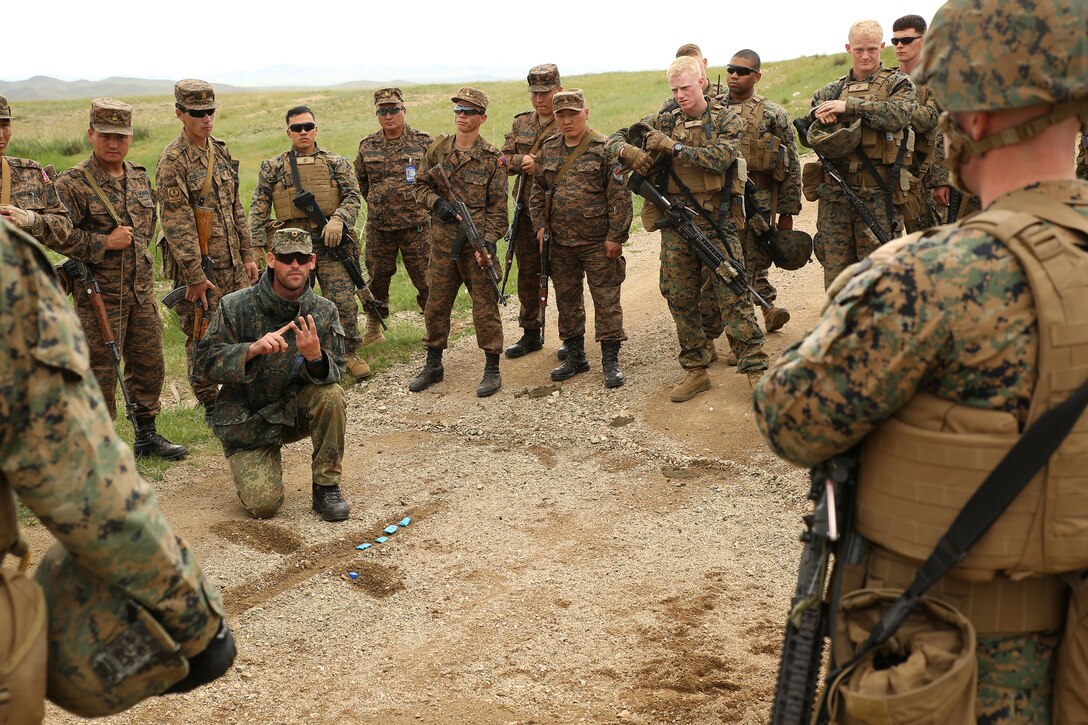 German Army Capt. Christian Seckler, kneeling, explains convoy tactics, techniques and procedures to Mongolian Armed Forces members and U.S. Marines and sailors June 23 at Five Hills Training Area, Mongolia, during convoy operations training at Exercise Khaan Quest 2014. KQ14 is a regularly scheduled, multinational exercise hosted annually by Mongolian Armed Forces and co-sponsored this year by U.S. Army, Pacific, and U.S. Marine Corps Forces, Pacific. KQ14 is the latest in a continuing series of exercises designed to promote regional peace and security. This year marks the 12th iteration of this training event. During the training, the service members searched for simulated improvised explosive devices and then practiced what they would do in a real-world situation. Seckler is an instructor at the German Armed Forces United Nations Training Center in Hammelburg, Germany, and an armed reconnaissance officer for the German Army. The Marines and sailors are with Company C, 1st Battalion, 8th Marine Regiment, which is currently assigned to 4th Marine Regiment, 3rd Marine Division, III Marine Expeditionary Force, under the unit deployment program. (U.S. Marine Corps photo by Cpl. Alyssa N. Gunton)