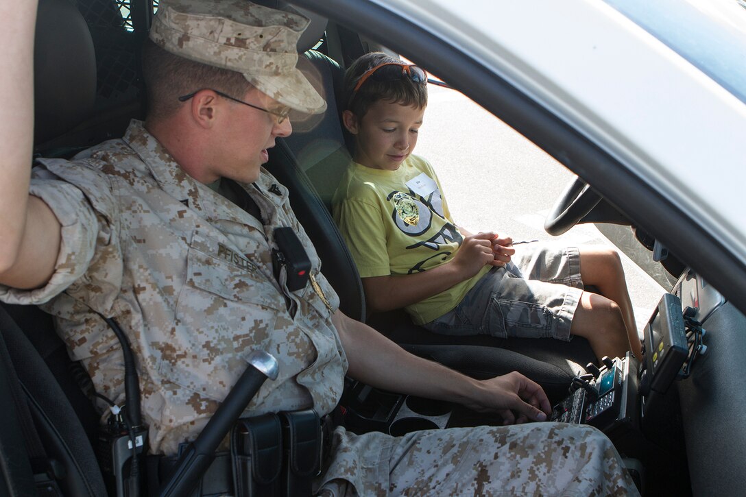 Cpl. Cody Pfister, a traffic investigator with the Provost Marshal’s Office and an Augusta, Ga., native, introduces Aidan Blackburn, 8, to the controls within a military police car during a Lil’ Leatherneck Day aboard Marine Corps Air Station Miramar, Calif., June 27. The event, hosted by Headquarters and Headquarters Squadron, introduced children of military parents to different aspects of the air station. 