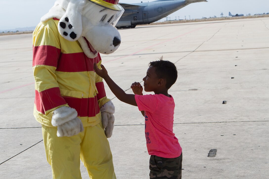 Jaden Brown, 5, plays with Sparky, Aircraft Rescue and Firefighting mascot, during a Headquarters and Headquarters Squadron Lil’ Leatherneck Day aboard Marine Corps Air Station Miramar, Calif., June 27. In addition to a demonstration by ARFF, the children explored other aspects of military life, such as military police, military working dogs, Explosive Ordnance Disposal, Indoor Simulated Marksmanship Trainer and air traffic control.
