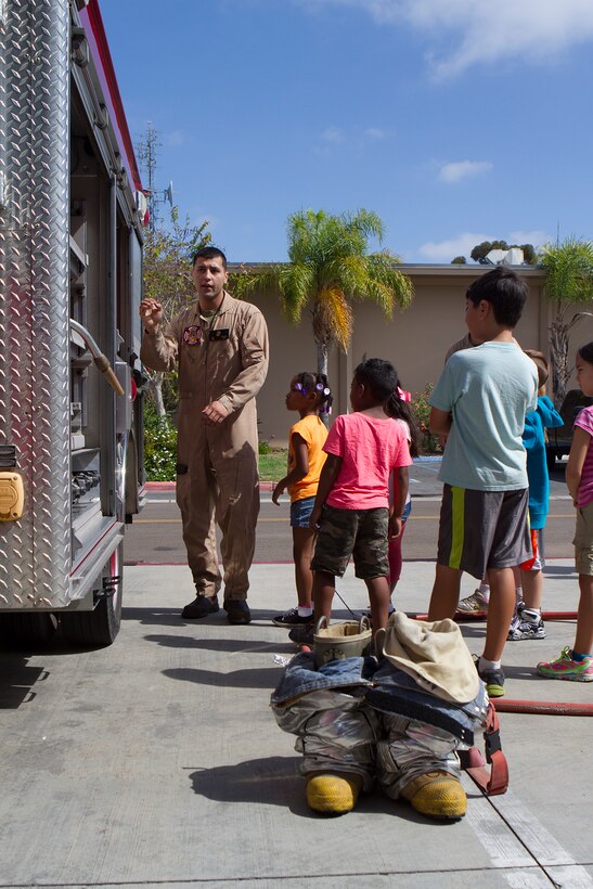 Pfc. Sergio Guillen, a rescueman with Aircraft Rescue and Firefighting, shows off tools on a fire truck during a Lil’ Leatherneck Day aboard Marine Corps Air Station Miramar, Calif., June 27. The Headquarters and Headquarters Squadron event promoted understanding between military families and the military lifestyle in an interactive way.
