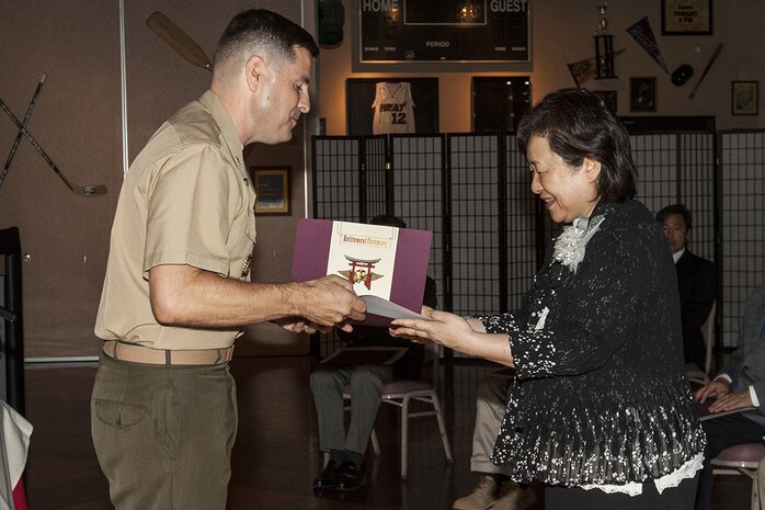Col. Robert Boucher, Marine Corps Air Station Iwakuni, Japan, commanding officer, hands a certificate of appreciation to a retiring Japanese employee during a retirement ceremony for Master Labor Contract and Independent Hire Agreement employees that took place in the Landing Zone inside Club Iwakuni Aboard Marine Corps Air Station Iwakuni, Japan, June 25, 2014.