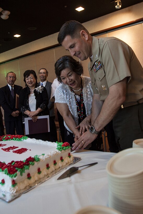 Col. Robert Boucher, Marine Corps Air Station Iwakuni, Japan, commanding officer, and Missie Hamano, a retiring Japanese employee, cut a cake during a retirement ceremony for Master Labor Contract and Independent Hire Agreement employees that took place in the Landing Zone inside Club Iwakuni Aboard Marine Corps Air Station Iwakuni, Japan, June 25, 2014.