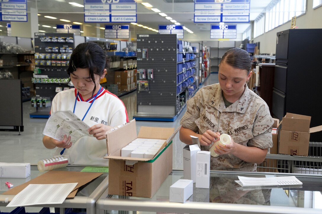 Yuka Shinzato, left, and Lance Cpl. Ashley C. Merrick place bar codes onto items for sale June 26 at the U.S. Marine Corps ServMart on Camp Foster. Shinzato was taught how to use the register, find items requested by customers, and restock shelves during her job shadow with the Base Supply Office, Marine Corps Base Camp Smedley D. Butler, Marine Corps Installations Pacific. Shinzato is an eighth grade student with Chatan Junior High School. Merrick is an Asheboro, North Carolina, native and supply administration and operations specialist with the office. 