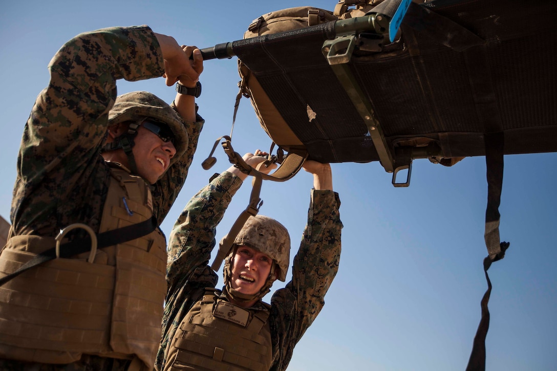 U.S. Marines with the 22nd Marine Expeditionary Unit hold a loaded stretcher over their heads during a physical conditioning drill as part of martial arts training in Camp Buehring, Kuwait, June 27, 2014. The Marines are conducting previously scheduled sustainment training to maintain proficiency and a high degree of readiness. The 22nd MEU is deployed with the Bataan Amphibious Ready Group as a theater reserve and crisis response force throughout U.S. Central Command and the U.S. 5th Fleet area of responsibility. (U.S. Marine Corps photo by Sgt. Austin Hazard/Released)