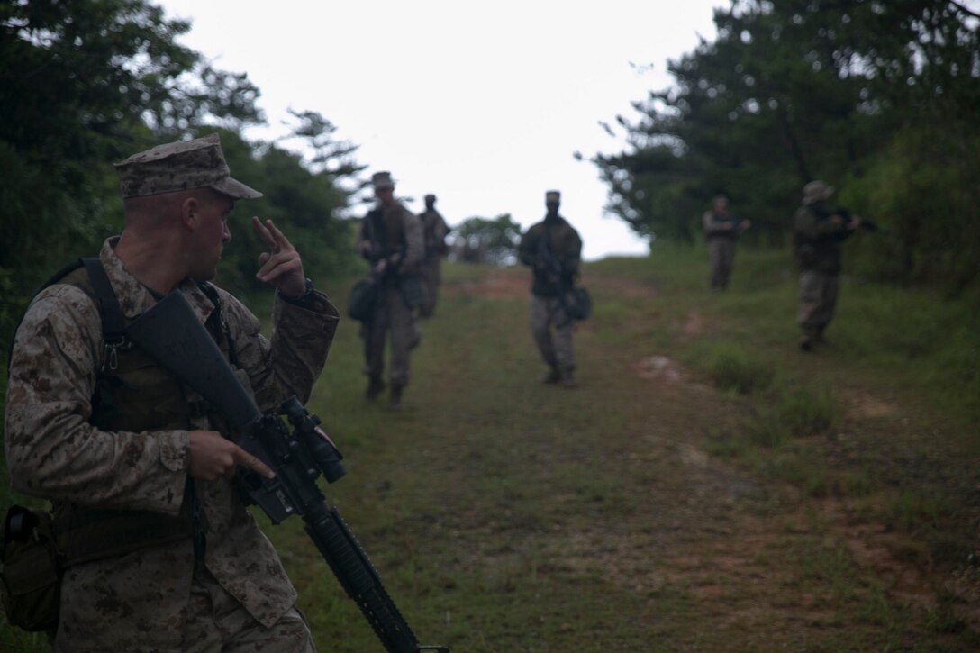 Lance Cpl. Robert K. Greff, left, gives a hand signal to his squad June 24 during Exercise Coral Thunder at Kadena Air Base. By using hand and arm signals the Marines were able to minimize the amount of noise they made while executing the simulated patrol. Greff is a Lincoln Park, New Jersey, native and aviation communication systems technician with Marine Air Support Squadron 2, Marine Air Control Group 18, 1st Marine Aircraft Wing, III Marine Expeditionary Force.