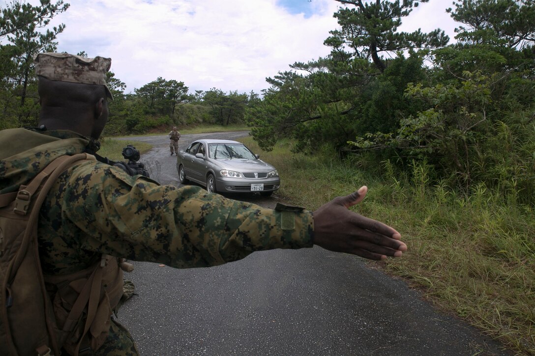Cpl. Damion M. Gaskin directs a vehicle through a simulated checkpoint June 24 during Exercise Coral Thunder at Kadena Air Base. The vehicle checkpoint provided Marines an opportunity to train for different scenarios they may encounter during a deployment. Gaskin is a Bradenton, Florida, native and ground radio repairer with Marine Air Support Squadron 2, Marine Air Control Group 18, 1st Marine Aircraft Wing, III Marine Expeditionary Force.